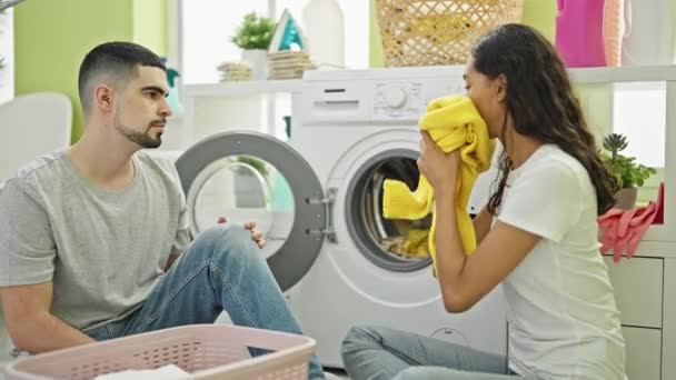 笑着坐在洗衣房地板上的一对美丽的夫妇 享受着新鲜干净衣服的味道 共同度过了一个温馨的家庭时光 — 图库视频影像