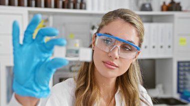 Genç, ciddi yüzlü, güvenlik gözlüğü takmış, laboratuvarda araştırma yapan, tıp bilimine adanmış çekici bir fener örneğine yakından bakan sarışın bir bilim adamı.. 