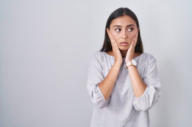 Young hispanic woman standing over white background tired hands covering face, depression and sadness, upset and irritated for problem 