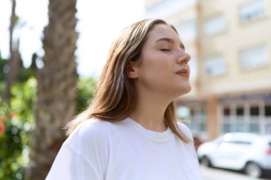 Parkta gözleri kapalı beyaz bir kadın nefes alıyor.