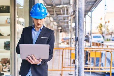 Young man architect using laptop at street