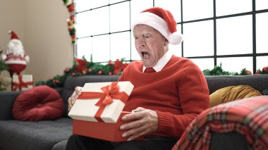Sunbae, Noel şapkası takıp hediyeleri açıyor ve evde şaşkın şaşkın oturuyor.