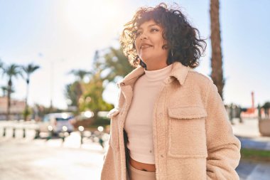 Young beautiful hispanic woman smiling confident looking to the side at street