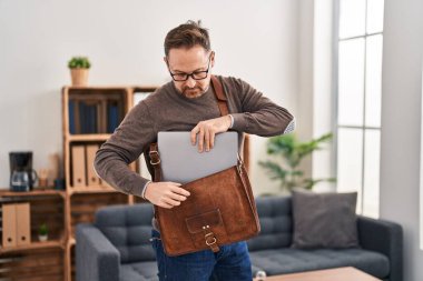 Young caucasian man business worker holding laptop of briefcase at office