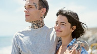 Güzel bir çift birbirine sarılıyor. Sahilde ciddi bir yüzle duruyorlar.