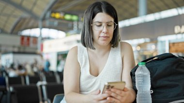 Havaalanında akıllı telefon kullanan güzel bir İspanyol kadın.