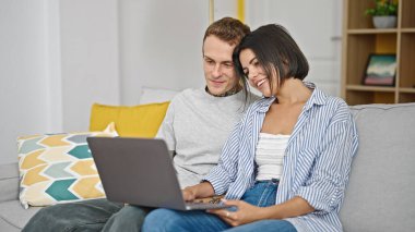 Güzel bir çift evdeki bilgisayarı kullanarak kanepede oturuyor.