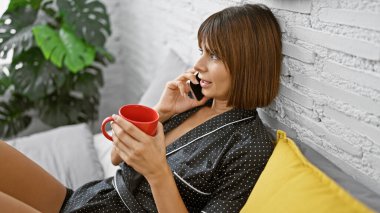 Sabahlar yakalandı, genç İspanyol güzeli yatak odasında rahat bir şekilde uzanmış, rahatlamış bir şekilde bir fincan kahve içip, akıllı telefonuyla konuşuyor.