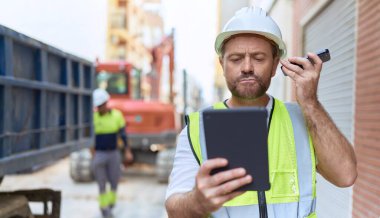 Orta yaşlı mimar, akıllı telefondan caddede touchpad kullanarak sesli mesaj dinliyor.