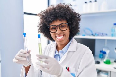 Laboratuvarda test tüpleri tutan Afrikalı Amerikalı kadın bilim adamı.