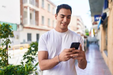 Sokakta akıllı telefon kullanan, kendine güvenen genç bir İspanyol.