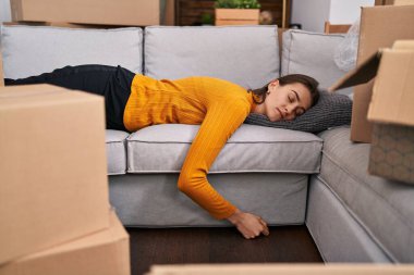 Beyaz bir kadın kanepeye uzanmış, yeni evinde uyuyor.