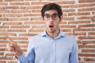 Duvarın arkasında dikilen Latin asıllı genç adam parmağını yana doğru kaldırarak şaşırdı, ağzı açık hayret içinde kaldı.. 