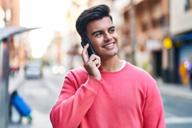 Genç İspanyol adam gülümsüyor. Kendine güveniyor. Sokakta akıllı telefondan konuşuyor.