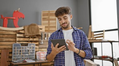 Gülümseyen genç Arap adam marangozluk işini üstlenir, dokunmatik dokunmatik teknolojiyi kendi kapalı atölyesinde benimser.