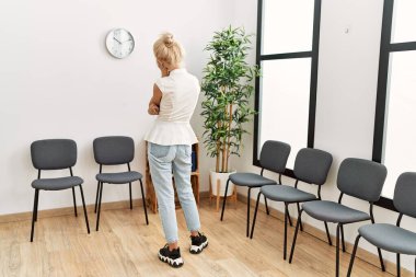 Sarışın genç kadın bekleme odasında geriye doğru bakıyor.