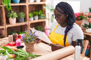 Afrikalı Amerikalı kadın çiçekçi çiçekçide evrak okuyor.