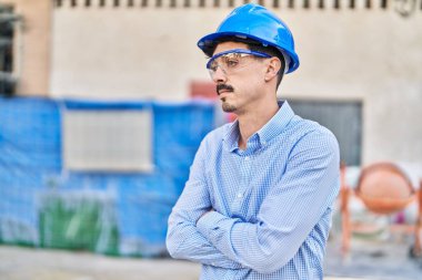 Young caucasian man architect standing with arms crossed gesture and relaxed expression at street