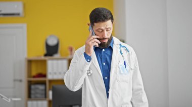 Genç İspanyol doktor klinikte akıllı telefondan konuşuyor.