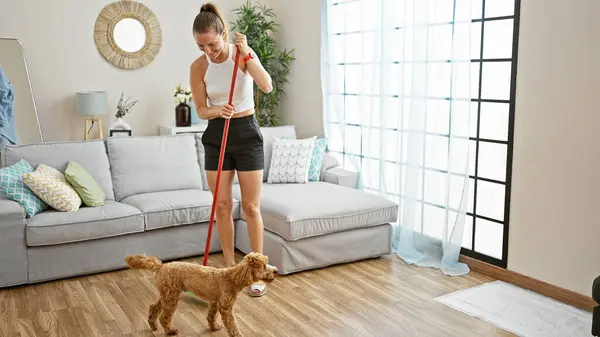 Young caucasian woman with dog cleaning floor at home
