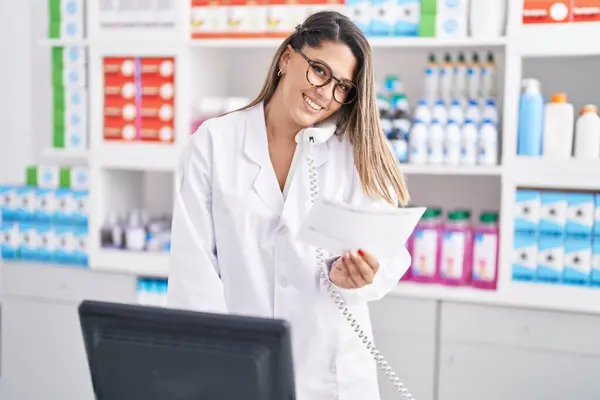 Young Hispanic Woman Pharmacist Talking Telephone Reading Prescription Pharmacy — Stockfoto