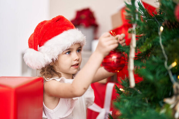 Adorable caucasian girl decorating christmas tree at home