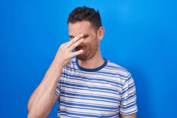 Young Hispanic Man Standing Blue Background Smelling Something Stinky Disgusting — Foto de Stock