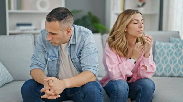 Man and woman angry couple sitting on sofa together at home