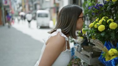 Çarpıcı İspanyol kadın Tokyo 'nun kentsel çiçeğinin canlı kokusunun tadını çıkarıyor. Gözlükleri şehrin modern cazibesini yansıtıyor..