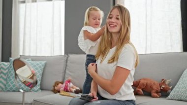 Kafkas anne ve kızı rahat bir şekilde kanepede oturuyor, güvenle birbirlerinin saçlarını tararken gülümsüyorlar evlerindeki rahat oturma odalarında..