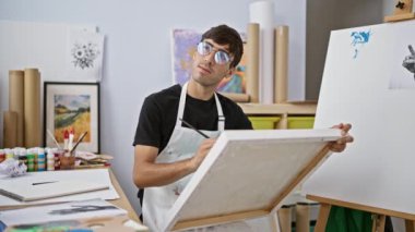 Çekici genç İspanyol bir adam, hevesli bir sanatçı, bir üniversite sanat stüdyosunda resim çizerken, elinde palet ve sehpada tuval ile düşüncelere dalmış..