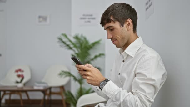 Молодий Іспаномовний Чоловік Використовує Смартфон Сидячи Стільці Залі Очікування — стокове відео