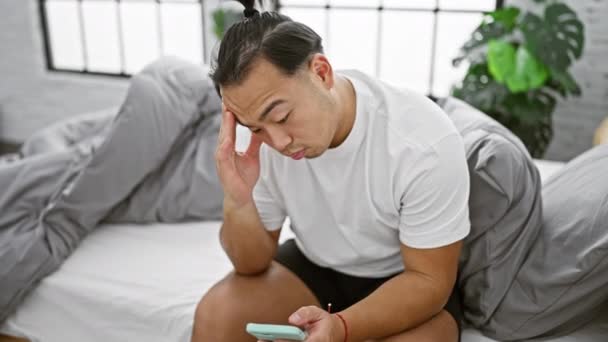Стресс Молодой Китаец Сидит Спальне Используя Смартфон Испытывая Серьезный Стресс — стоковое видео