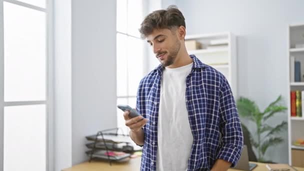 年轻人 大拇指抬起来 用智能手机钉在办公室里 带着得意洋洋的微笑 表现出老板般的自信 — 图库视频影像
