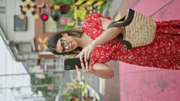 Усміхнена Красива Іспаномовна Жінка Окулярах Використовує Телефон Галасливій Вулиці Токіо — стокове відео
