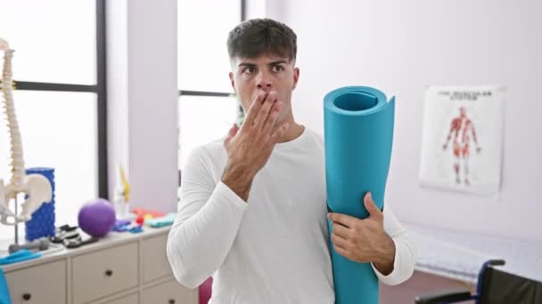 Young Hispanic Man Holding Yoga Mat Covering Mouth Hand Shocked — Stock Video