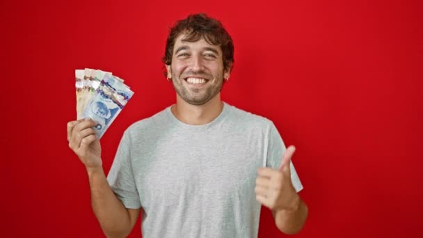 쾌활한 자신감으로 엄지손가락으로 자신의 캐나다 지폐를 보여주는 미소와 활기찬 빨간색 — 비디오