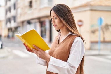 Sokakta kitap okuyan genç, güzel İspanyol kadın.