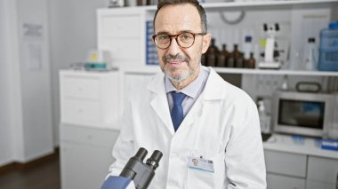 Gri saçlı, gülümseyen orta yaşlı bir adam laboratuarda çığır açan bir şey keşfetti. Kendine güvenen bilim adamı elleri mikroskop üzerinde çalışıyor. Kapalı alandaki tıbbi araştırma merkezinin profesyonel vızıltıları arasında..