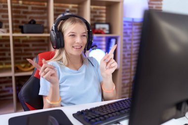 Video oyunları oynayan, kulaklık takan, kendine güvenen, farklı yönleri gösteren genç, beyaz bir kadın. reklam için kopyalama alanı 