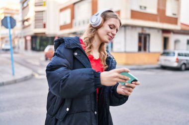 Sokakta video oyunu oynarken kendine güvenen genç sarışın kadın.