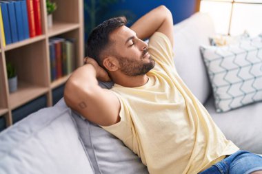 Genç İspanyol adam, ellerini başının üstüne koyup evinde kanepede oturarak rahatladı.