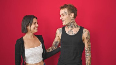 Güzel çift gülümsüyor. Birbirlerine güveniyorlar. Kırmızı arka planda konuşuyorlar.