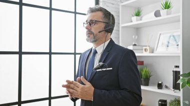 Genç, Latin asıllı, kır saçlı, iş adamı. Elleri boşta, ofiste yürüyor.