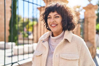 Young beautiful hispanic woman smiling confident looking to the side at street