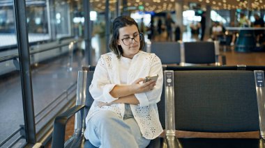 Havaalanında akıllı telefon kullanan güzel, genç bir İspanyol kadın.