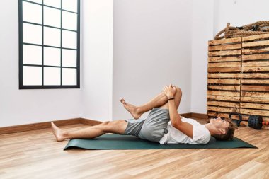 Spor merkezinde kendine güvenen, gülümseyen beyaz bir genç.