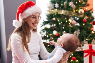 Anne ve oğul Noel ağacının yanında duruyorlar.