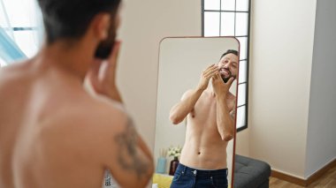 Genç İspanyol adam sakala dokunup aynaya bakıyor.