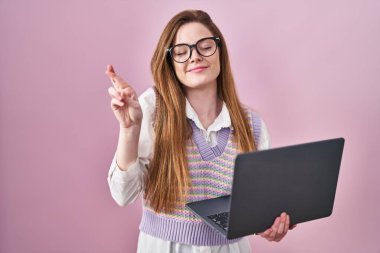 Bilgisayarda çalışan beyaz bir kadın umut ve gözlerin kapalı bir şekilde dua ederek işaret ediyor. Şans ve batıl inançlar. 